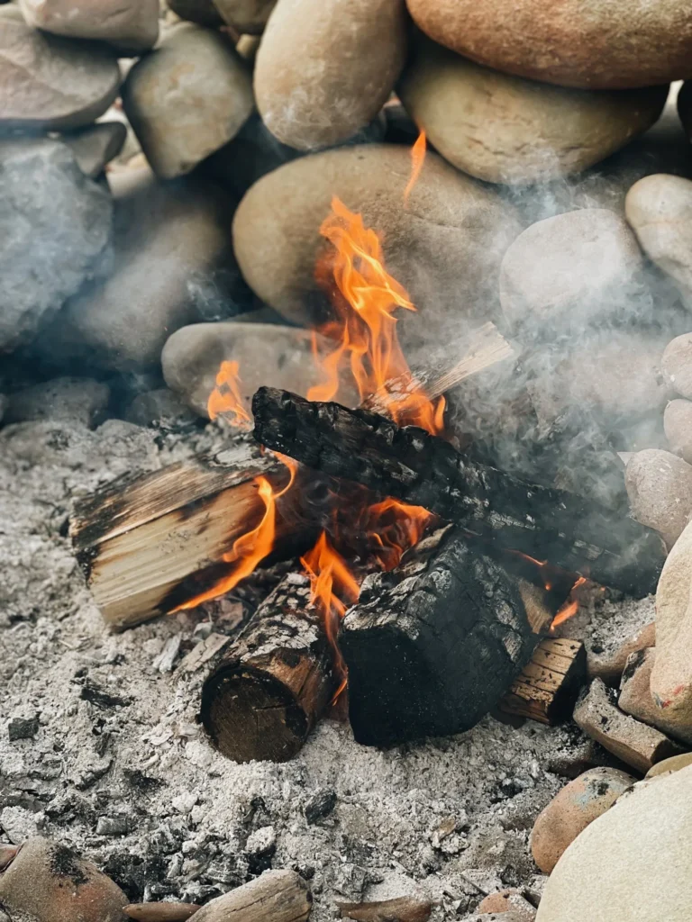 Person maintaining a wood fire pit, highlighting essential upkeep tasks for safety